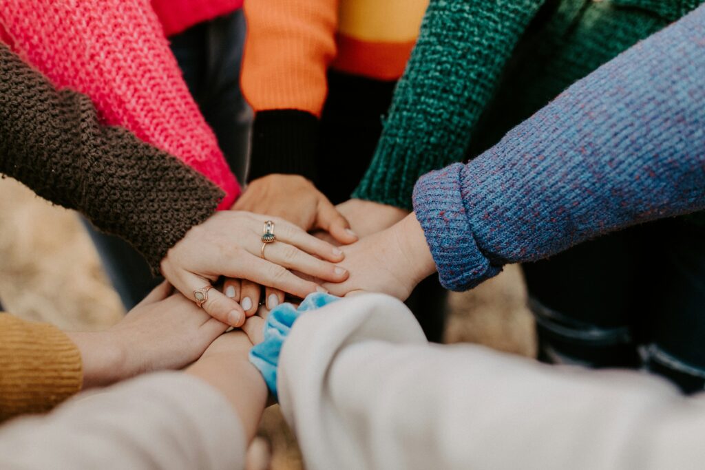 Diverse hands in colorful clothing reaching together to pile on top of one another.